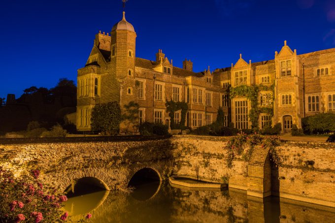 Kentwell Hall seen at floodlit at night with surrounding moat